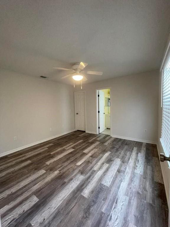 spare room with dark wood-style floors, ceiling fan, a textured ceiling, and baseboards