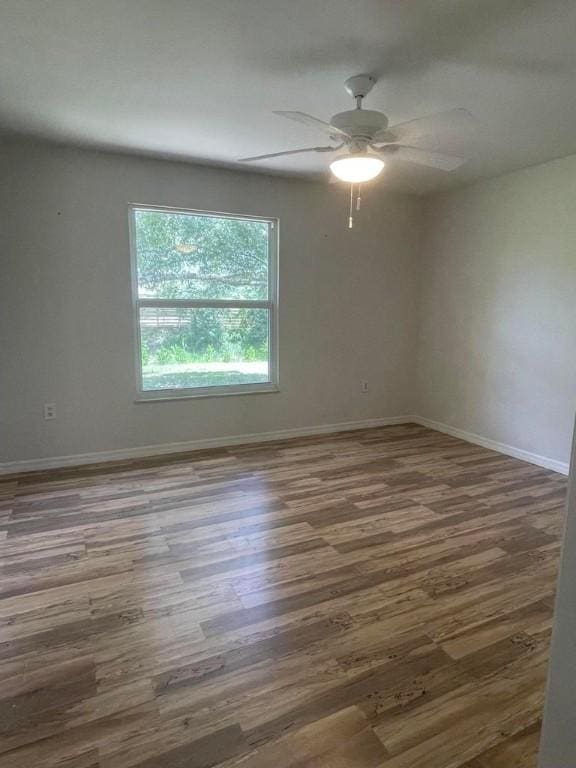 empty room with ceiling fan, baseboards, and wood finished floors