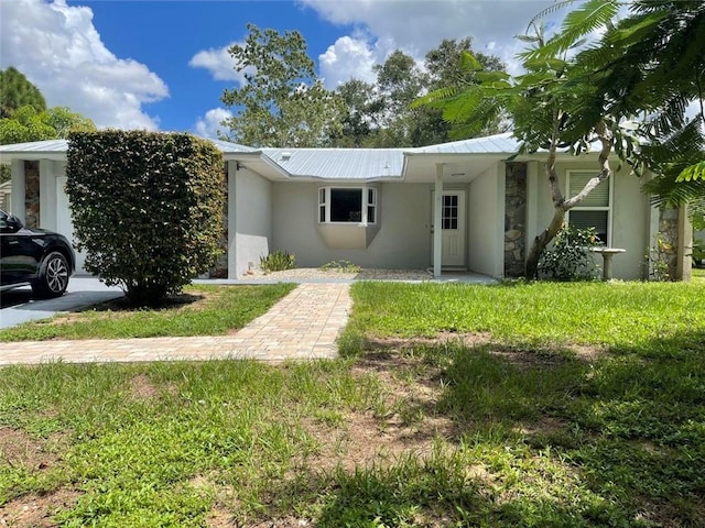 view of front of house featuring metal roof, a front lawn, and stucco siding