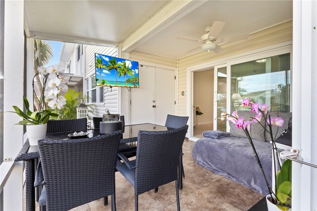 sunroom / solarium featuring beamed ceiling and ceiling fan