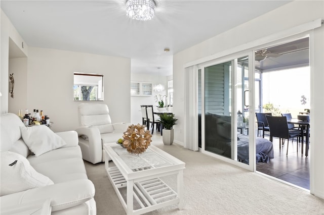 carpeted living room featuring an inviting chandelier