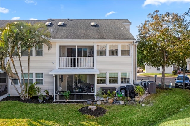 back of property featuring a balcony and a lawn