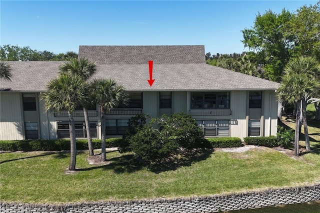 view of front of home with roof with shingles and a front yard