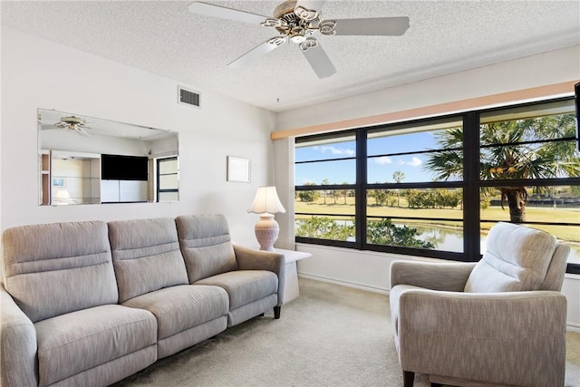 living area featuring visible vents, carpet flooring, and a textured ceiling