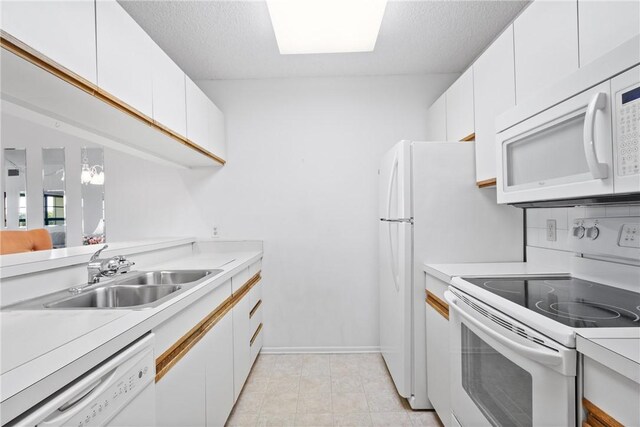 kitchen featuring a sink, light countertops, white appliances, and white cabinetry