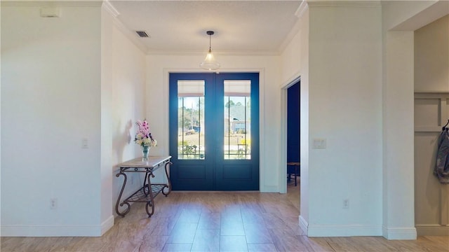 entryway with crown molding and french doors