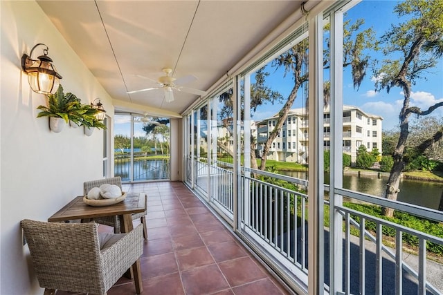 sunroom / solarium with ceiling fan and a water view