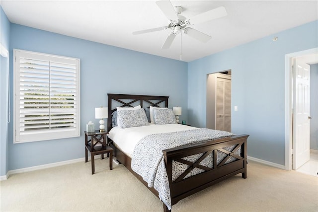 bedroom with light carpet, a closet, a ceiling fan, and baseboards