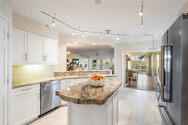 kitchen with decorative backsplash, appliances with stainless steel finishes, ornamental molding, a peninsula, and white cabinetry