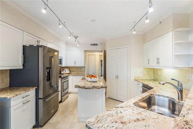 kitchen with appliances with stainless steel finishes, a sink, light stone countertops, and a center island