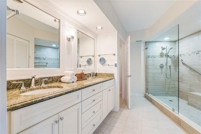 bathroom with tile patterned floors, a sink, a tile shower, and double vanity