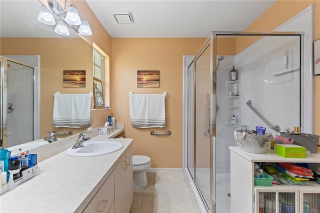 bathroom with toilet, vanity, tile patterned floors, and a shower with shower door