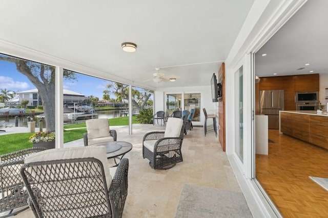 sunroom / solarium with a water view and ceiling fan