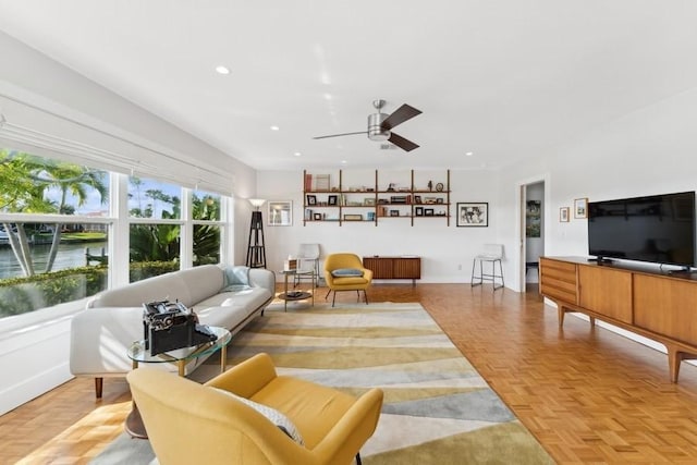 living room featuring a water view, ceiling fan, and light parquet flooring