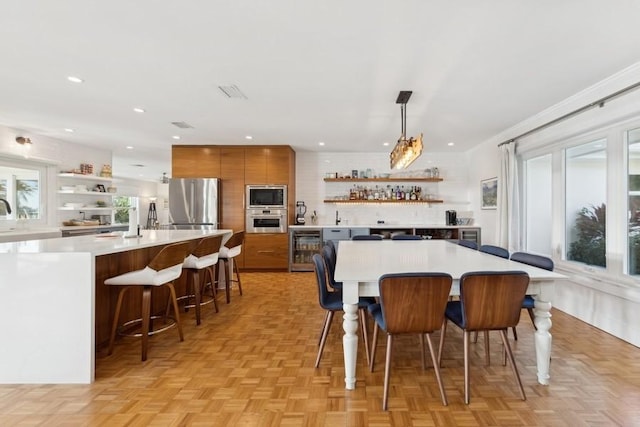 dining space with wine cooler, light parquet floors, and bar area