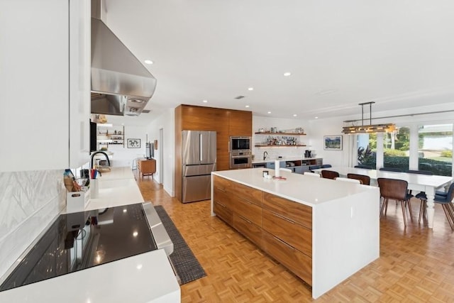 kitchen with a spacious island, light parquet flooring, appliances with stainless steel finishes, and sink