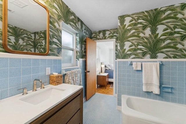 bathroom featuring vanity, a washtub, and tile walls