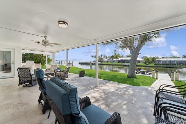 view of patio featuring a water view, an outdoor hangout area, an outdoor kitchen, and ceiling fan