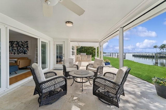 view of patio with a water view, an outdoor kitchen, and ceiling fan