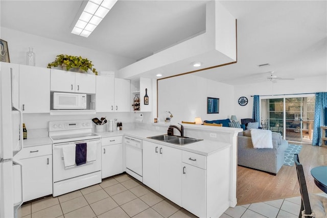 kitchen featuring a sink, light tile patterned floors, a peninsula, open floor plan, and white appliances