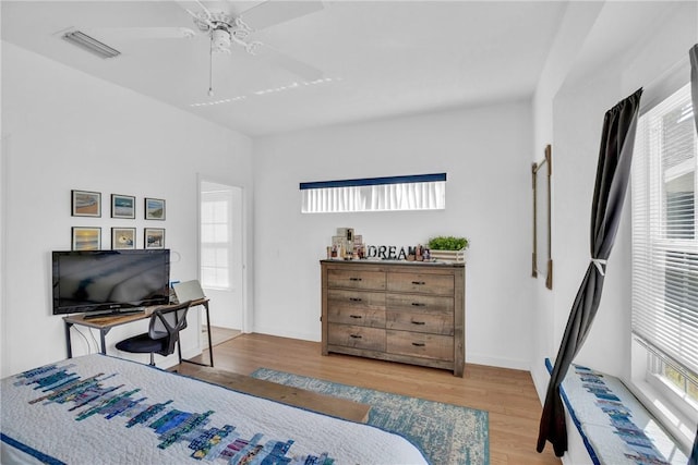 bedroom with a ceiling fan, wood finished floors, and visible vents