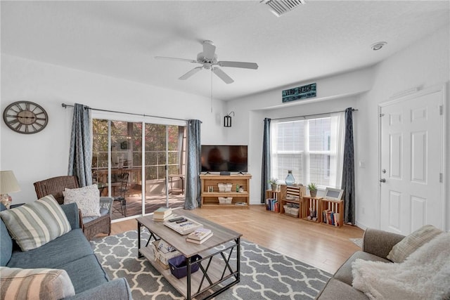 living room featuring a ceiling fan, visible vents, and wood finished floors