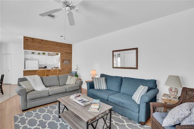 living room featuring a ceiling fan, visible vents, and light wood-style floors