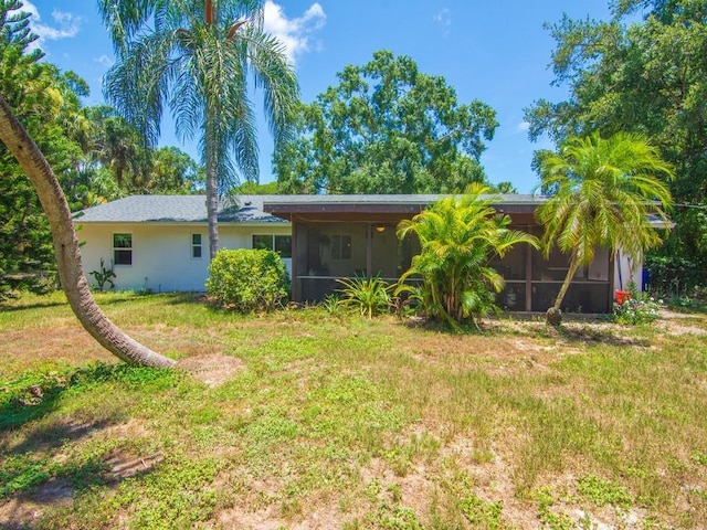 6345 7th Ln, Vero Beach, FL 32968 - rear view of property with a sunroom, a lawn, and stucco siding