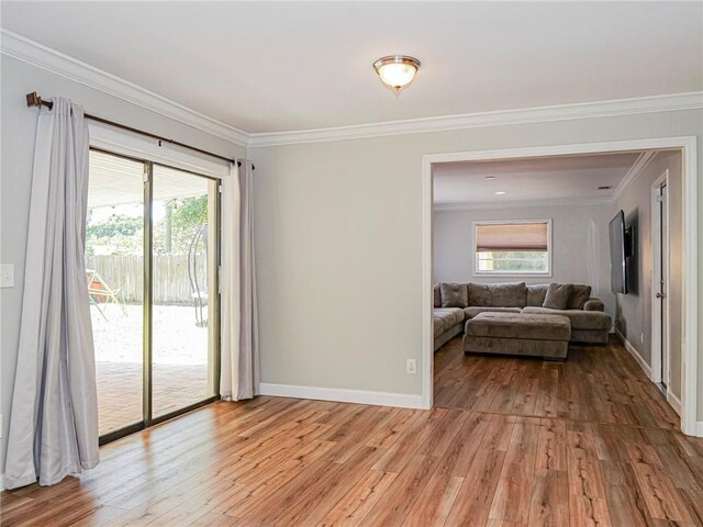 empty room with crown molding, light wood-style flooring, healthy amount of natural light, and baseboards