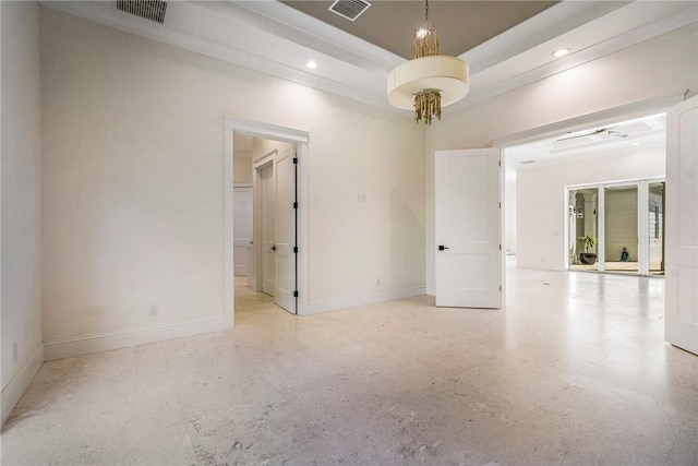 spare room with visible vents, a raised ceiling, and baseboards