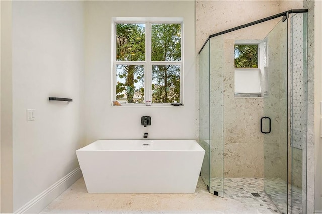 full bathroom with plenty of natural light, a shower stall, baseboards, and a freestanding tub