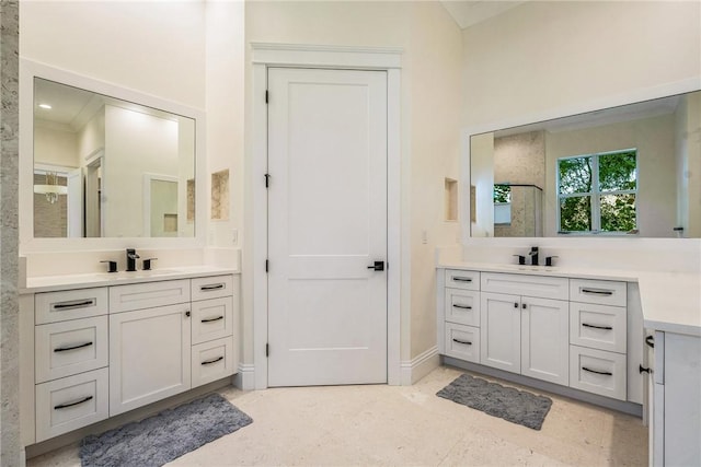 bathroom with a sink, baseboards, two vanities, and walk in shower