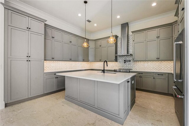 kitchen with high end fridge, gray cabinetry, ornamental molding, a sink, and wall chimney range hood