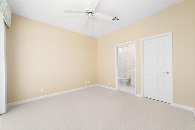 unfurnished bedroom featuring ceiling fan, light colored carpet, and ensuite bath