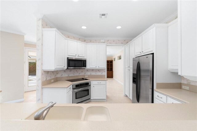 kitchen featuring appliances with stainless steel finishes, sink, white cabinets, light tile patterned floors, and crown molding