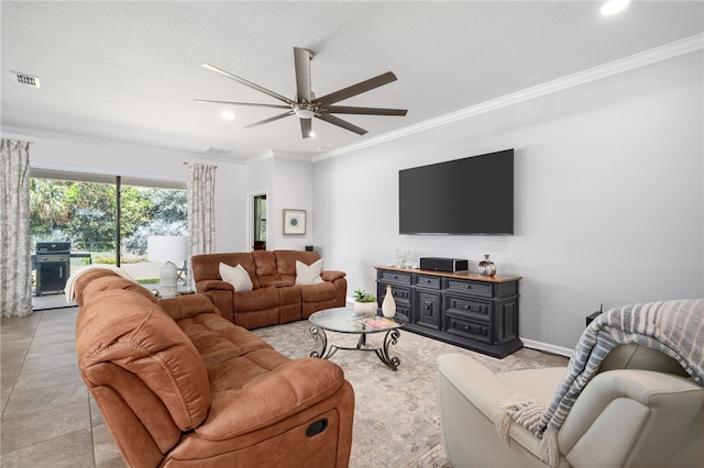 living room featuring a textured ceiling, light tile patterned floors, ceiling fan, and crown molding