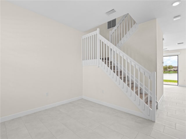 stairway featuring a water view and tile patterned floors