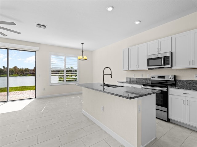 kitchen featuring decorative light fixtures, stainless steel appliances, white cabinetry, and a water view