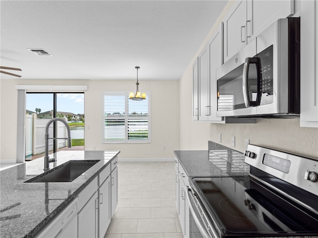 kitchen featuring white cabinets, sink, hanging light fixtures, dark stone countertops, and stainless steel appliances