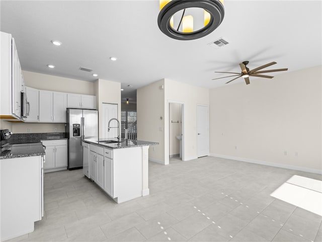 kitchen featuring a kitchen island with sink, white cabinets, sink, dark stone countertops, and stainless steel appliances