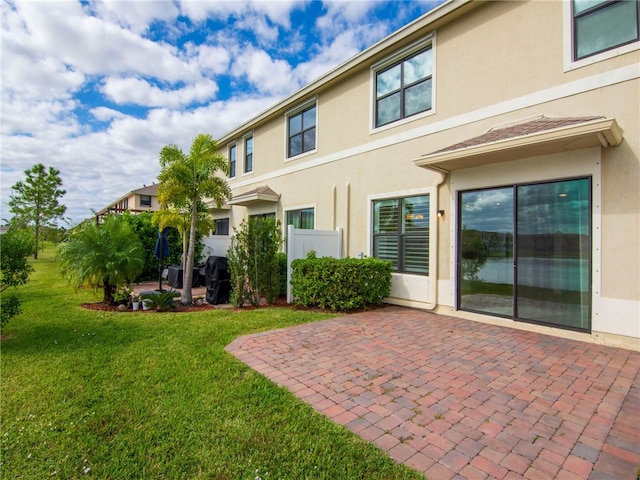 rear view of house featuring a lawn and a patio