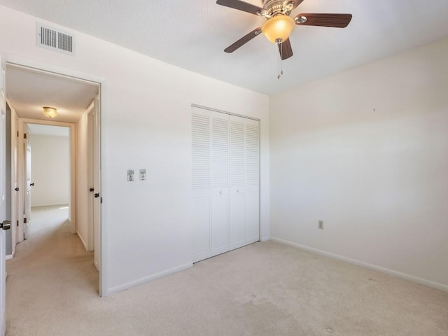 unfurnished bedroom featuring ceiling fan, light colored carpet, and a closet