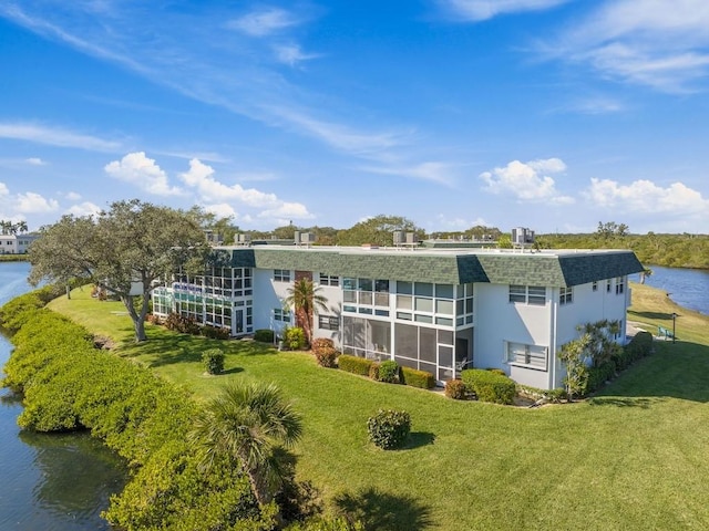 rear view of property with a lawn and a water view