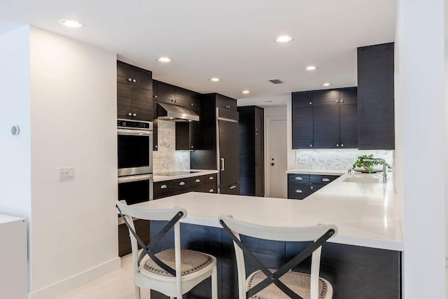 kitchen with kitchen peninsula, a breakfast bar, sink, and decorative backsplash