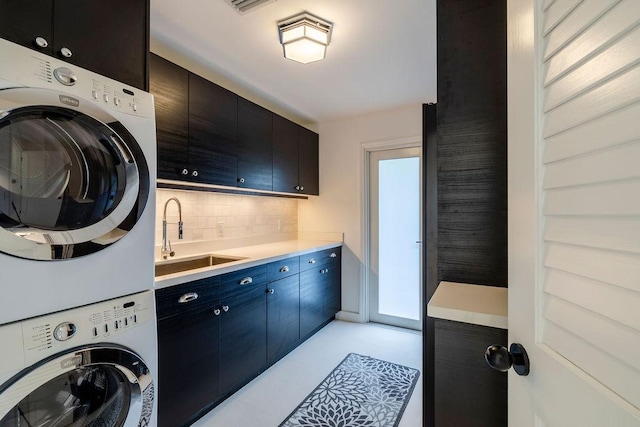 laundry room with cabinets, stacked washing maching and dryer, and sink