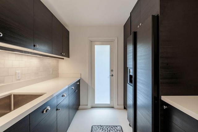 kitchen featuring black fridge with ice dispenser, sink, and decorative backsplash