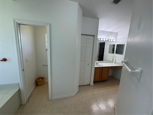2054 14th Ave SW, Vero Beach, FL 32962 - bathroom with double vanity, a closet, a textured ceiling, and baseboards