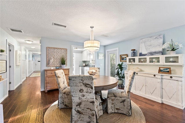 dining room featuring a textured ceiling, sink, dark wood-type flooring, and a chandelier