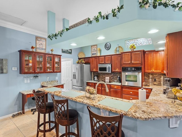 kitchen with tasteful backsplash, stainless steel appliances, a kitchen bar, and kitchen peninsula