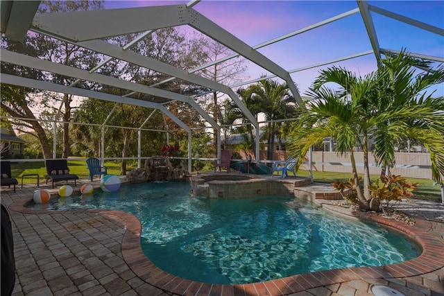 pool at dusk with an in ground hot tub, a lanai, and a patio